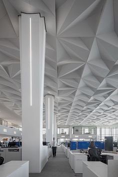 an office with white walls and ceilinging is pictured in this image, there are people working at their desks