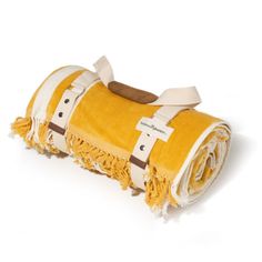 a yellow and white blanket with tassels on it's ends is laying down