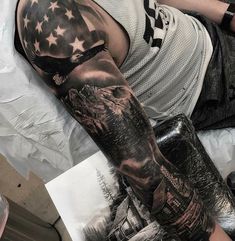 a man laying on top of a bed next to a book with an american flag tattooed on his arm