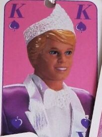 a barbie doll wearing a tiara and holding a card in her hand with the letter k on it