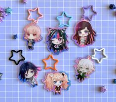 six anime character shaped keychais on a blue surface with stars and confetti