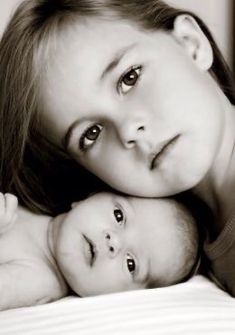 a mother and baby laying on top of each other in black and white, looking at the camera