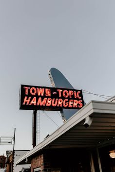 the sign for town - topic hamburgers is lit up in red and black