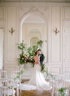 a bride and groom standing in front of an arch decorated with greenery at their wedding