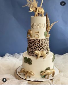 a three tiered cake decorated with gold animal and giraffes on top