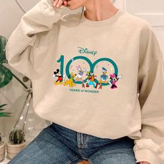 Disney 100 Years Of Wonder Sweatshirt Disney Crew Neck Sweatshirt For Fans, Disney Crew Neck Sweatshirt Fan Merchandise, Disney Fan Merchandise Crew Neck Sweatshirt, Disney Long Sleeve Fan Merchandise Tops, White Letter Print Sweatshirt For Disney Fan Events, White Letter Print Sweatshirt For Disney Events, White Disney Character Print Sweatshirt For Fan Events, Disney Long Sleeve Fan Merchandise T-shirt, White Graphic Print Sweatshirt For Disney Fan Events