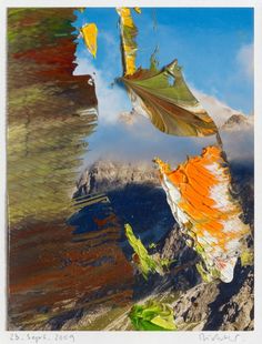 an abstract photograph of leaves floating in the air on top of a mountain with blue sky and clouds behind them