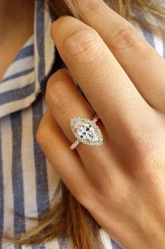 a woman's hand with a diamond ring on her finger and a striped shirt