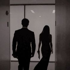 a man and woman standing in front of an open door with their hands behind them