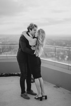 a man and woman kissing on top of a building