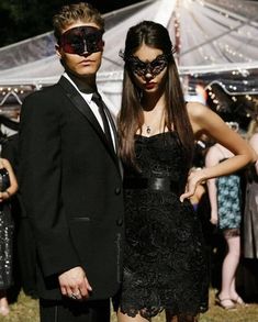 a man and woman in masquerades standing next to each other at an outdoor event