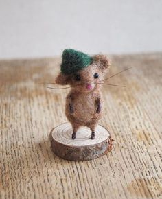 a tiny mouse with a green hat on top of a wooden stump