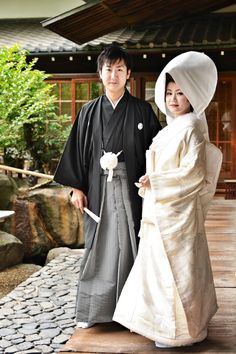 a man and woman dressed in traditional japanese garb standing next to each other on a wooden platform