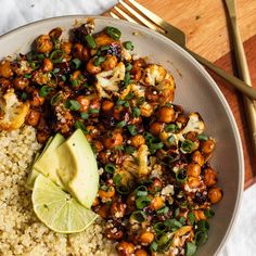 a white plate topped with cauliflower, rice and avocado