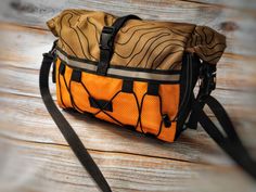 an orange and black bag sitting on top of a wooden table