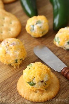 some food on a wooden table with a knife and green peppers in the background,