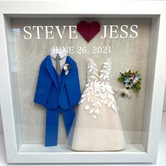 a wedding shadow frame with two bride and groom's outfits on display next to each other