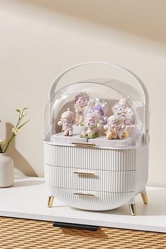 a white basket filled with teddy bears sitting on top of a table next to a vase