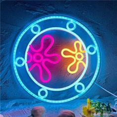 a neon sign that is on the side of a wall in front of a vase with flowers