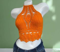 an orange crocheted crop top on a mannequin's torso,