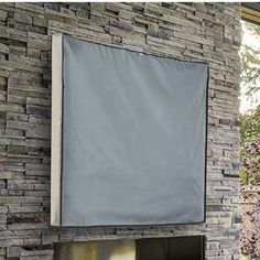 a fire place sitting under a window next to a stone wall with a gray covering over it