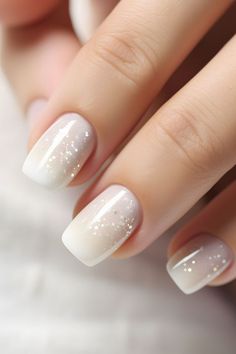 a woman's nails with white and gold glitters on them, while she is holding