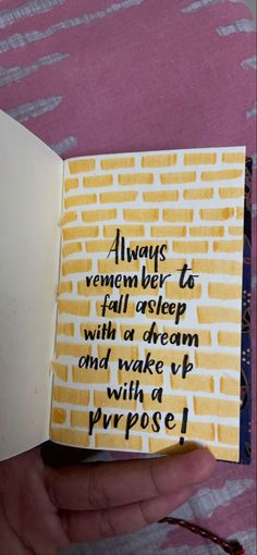 someone is holding an open book with writing on it that says, always remembers to fall asleep with a dream and wake up with a purpose