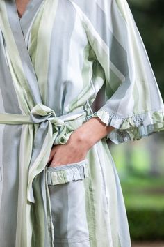 a woman is wearing a robe and has her hands on her hip as she stands outside