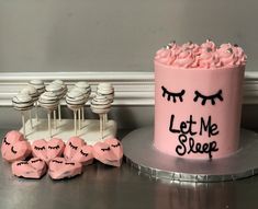 a pink cake sitting on top of a table next to cupcakes