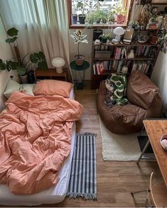 a small bedroom with a bed, couch and book shelf in the corner next to a window