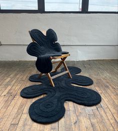 a black chair sitting on top of a hard wood floor next to a large window