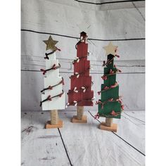 three small wooden christmas trees with decorations on them