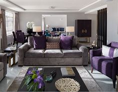 a living room with couches, chairs and tables in purple and grey colors on the walls