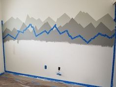 a room with mountains painted on the wall and blue tape taped to the walls around it