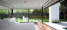 a bedroom with glass walls and wooden flooring next to a swimming pool in the backyard