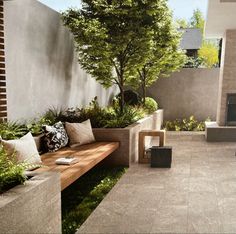 an outdoor seating area with trees and plants on the wall, next to a fire place