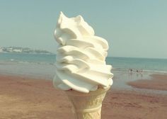 an ice cream cone on the beach with people in the background