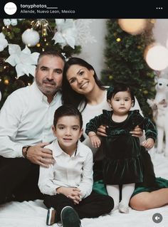 a family posing for a christmas photo in front of a christmas tree