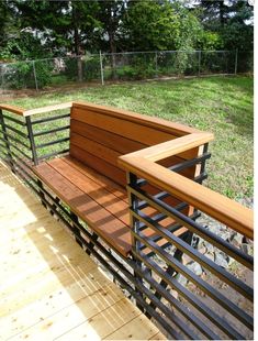 a wooden bench sitting on top of a wooden deck next to a fenced in area