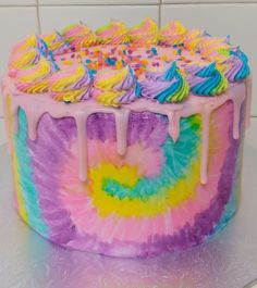 a tie dye cake with icing and sprinkles on the top is sitting on a counter