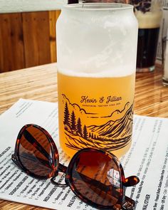 a beer and sunglasses sitting on top of a table next to each other in front of a mason jar