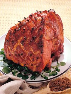 a piece of meat sitting on top of a white plate next to a wooden spoon