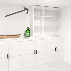 a room with white cabinets and green vases on the top shelf, along with an arrow painted on the wall