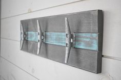 three metal airplane hooks mounted on the side of a white wooden wall with blue paint