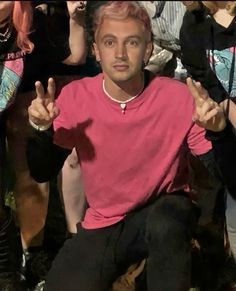 a man sitting in front of a group of people making the peace sign with his hands