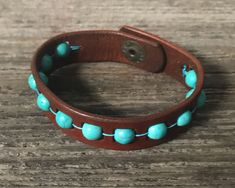 a brown leather bracelet with turquoise beads