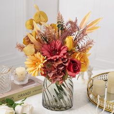 a vase filled with flowers sitting on top of a table next to candles and books