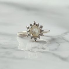 Sometimes when a girl says she likes to receive flowers as a gift, it's not the real flowers she means. Think twice and go for the safest thing - our Flora ring with Golden Rutile and Moissanites. Floral jewelry is where it's at! Perfect as a graduation gift, birthday gift, anniversary ring, or a promise ring. Details: Center stone Gemstone: Golden Rutile Stone Shape: Round Measurements: approx. 6mm Side stones Gemstone: Moissanite Shape: Round Measurements: 2mm (6), 1.5mm (6) Pictured in vermei Rose Cut Diamond Flower Promise Ring, Heirloom Flower Ring With Rose Cut Diamonds As Gift, White Rose Cut Diamond Ring For Proposal, Heirloom Rose Cut Diamond Flower Ring As Gift, White Diamond Flower Ring With Rose Cut, White Diamond Ring With Rose Cut Flower Shape, White Flower Ring With Gemstone For Promise, Flower Ring With Rose Cut Diamonds For Gifts, White Gemstone Flower Ring For Promise