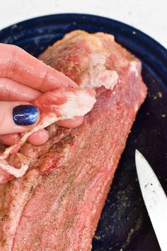 a woman is peeling the end of a piece of meat on a plate with a knife and fork