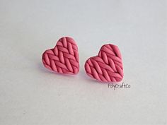 two pink heart shaped earrings sitting on top of a white table next to each other